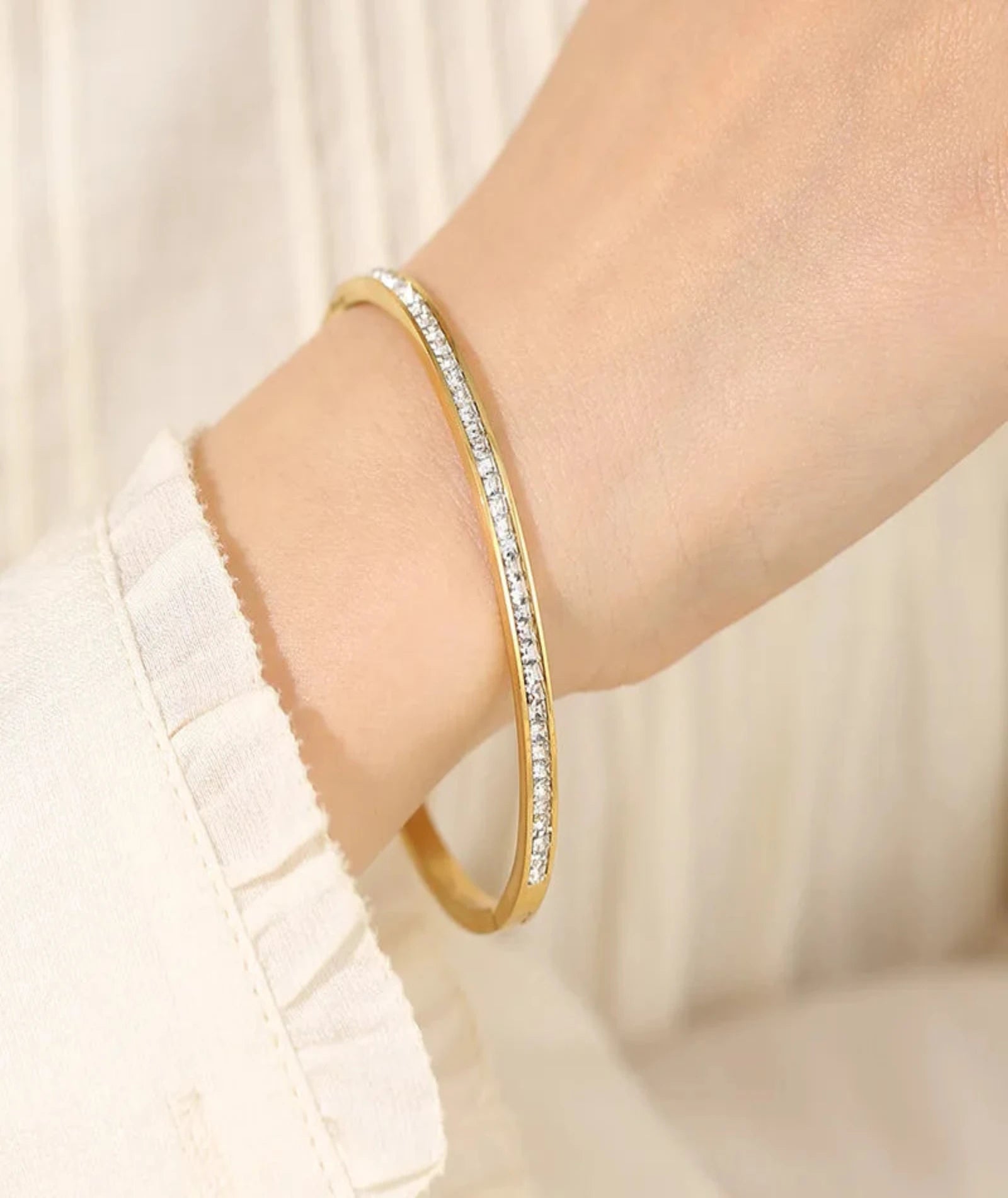 Gold bracelet with crystals on a wrist against a light background